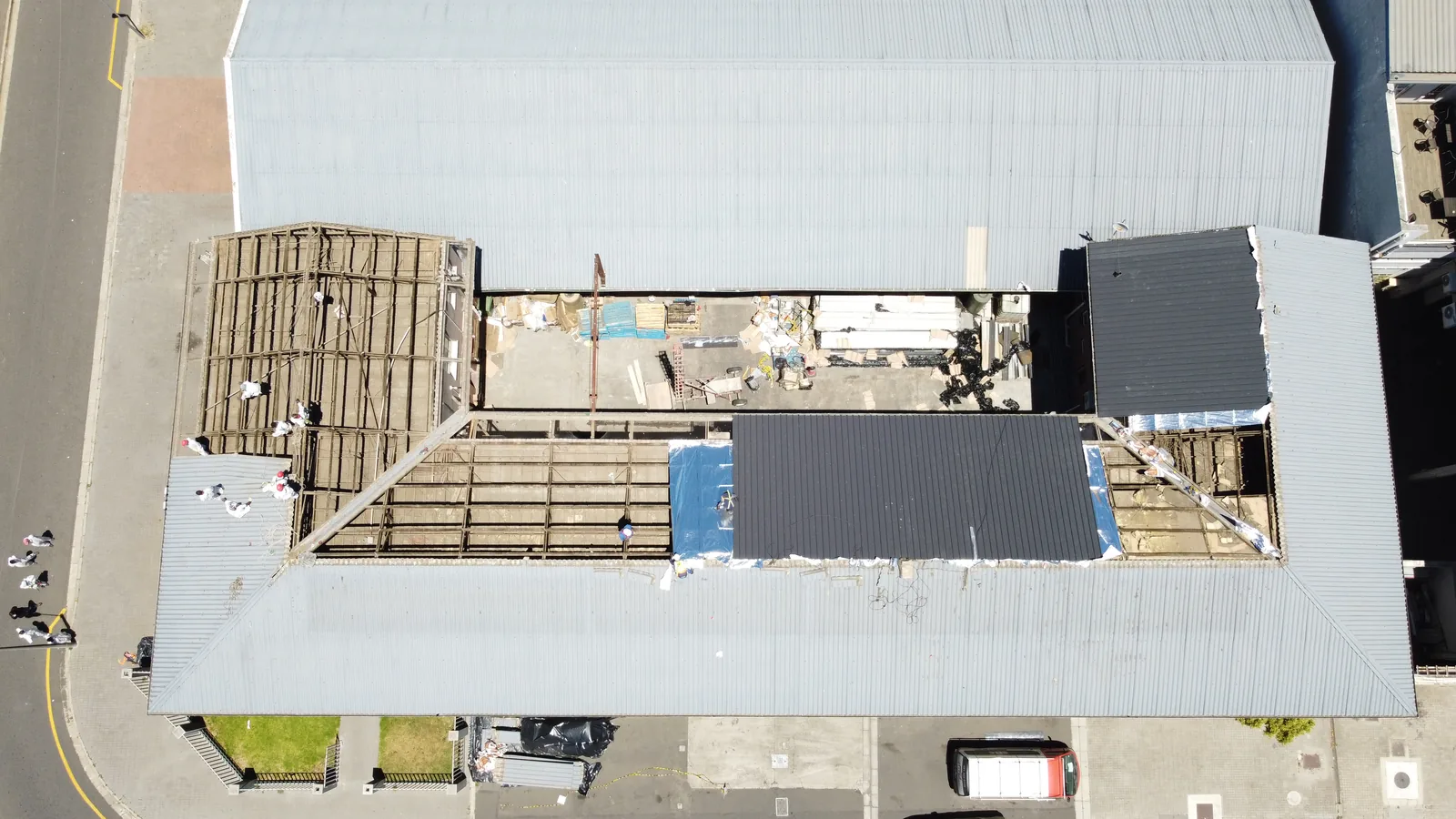 New dark roof sheets installed alongside an open section of roof framing