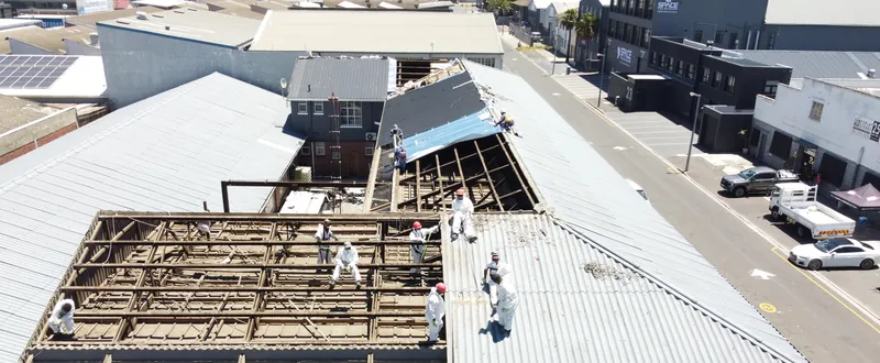 Overhead oblique view of exposed roof structure beside remaining corrugated sheets