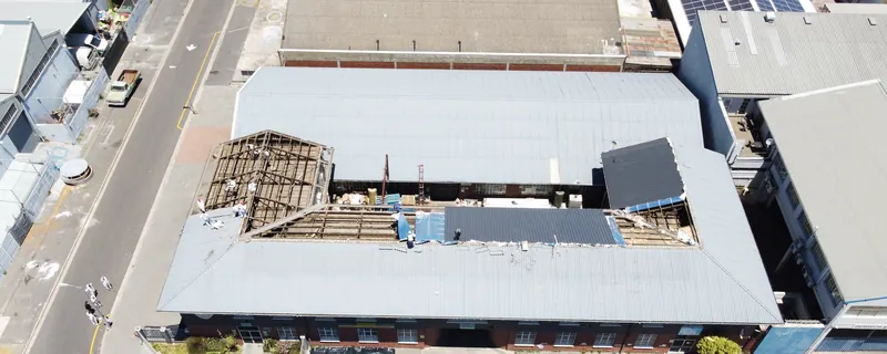 Aerial overview of remaining roof covering, exposed structure and sections of new roofing