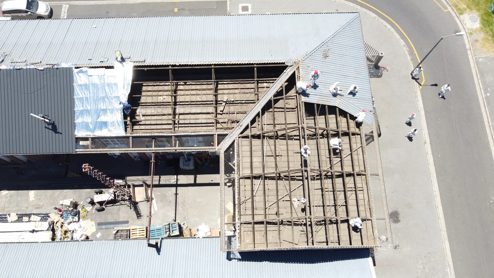Roof replacement in progress, with exposed roof framing beside remaining corrugated covering and newly fitted dark sheets