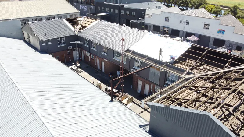 Exposed roof framing and underlay viewed from the opposite side of the courtyard