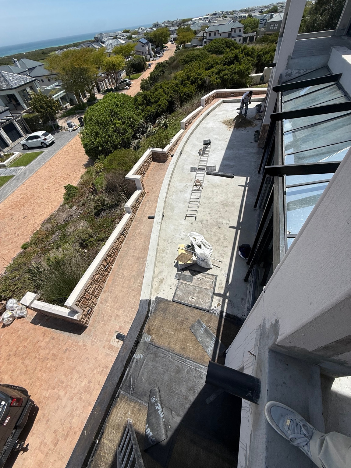 View down onto the lower balcony with waterproofing works and site materials in place
